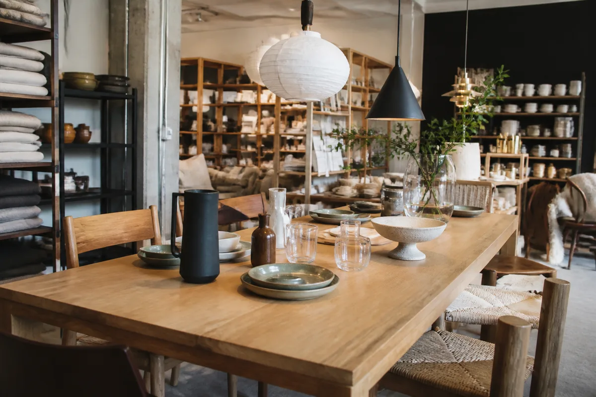 Espace de boutique présentant une table contemporaine entourée d’objets de décoration et de luminaires