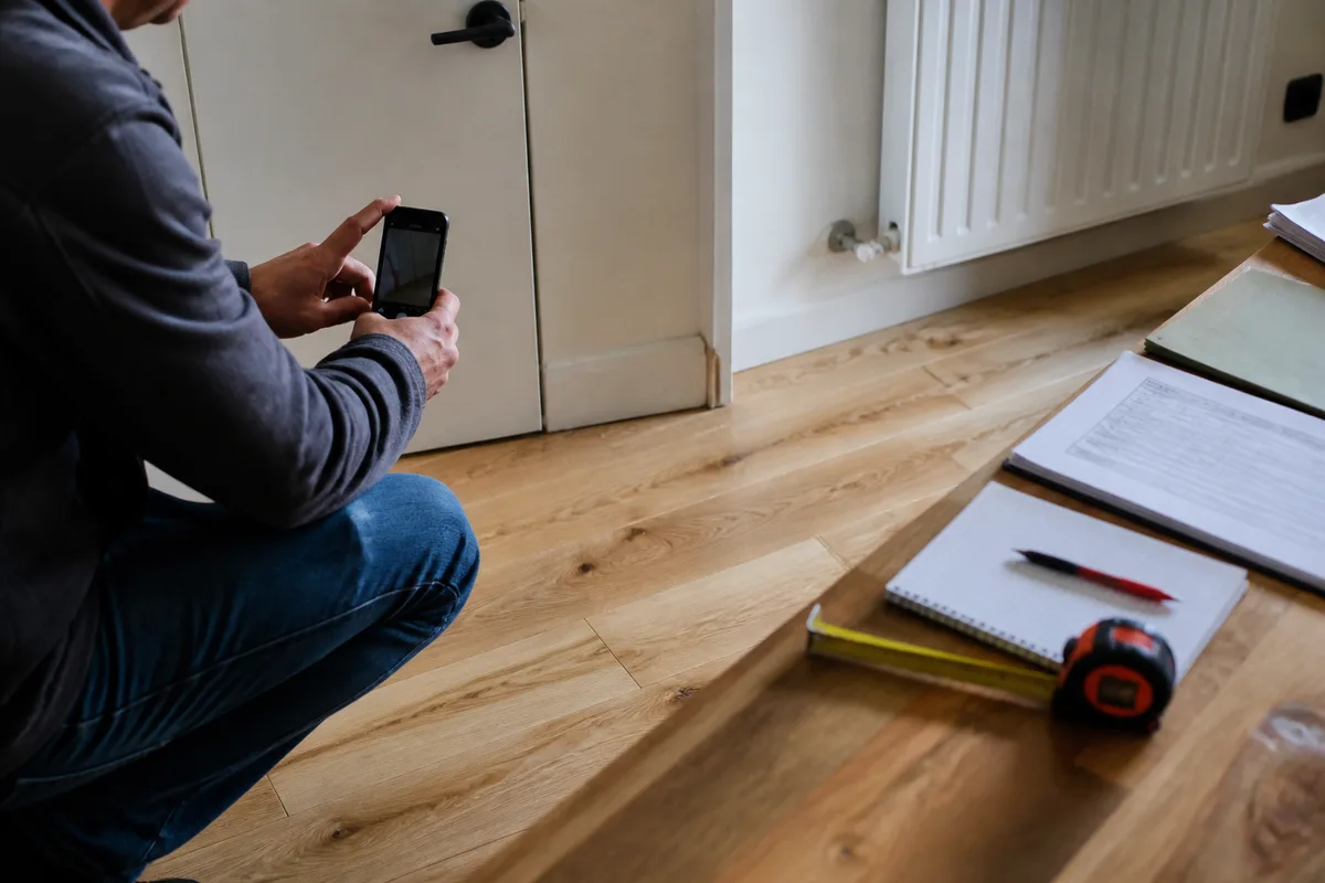 Contrôle avant solde des travaux dans une pièce rénovée avec outils et documents du chantier